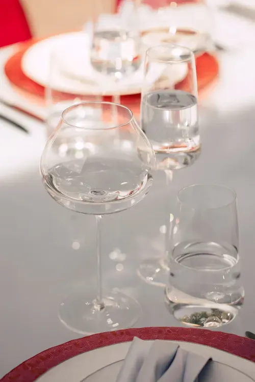 Современная сервировка с красными акцентами за белым прямоугольным столом